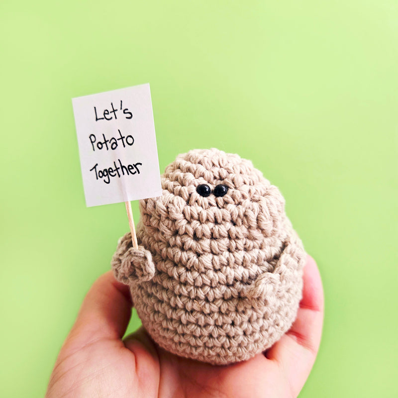 crochet potato holding a sign that says 