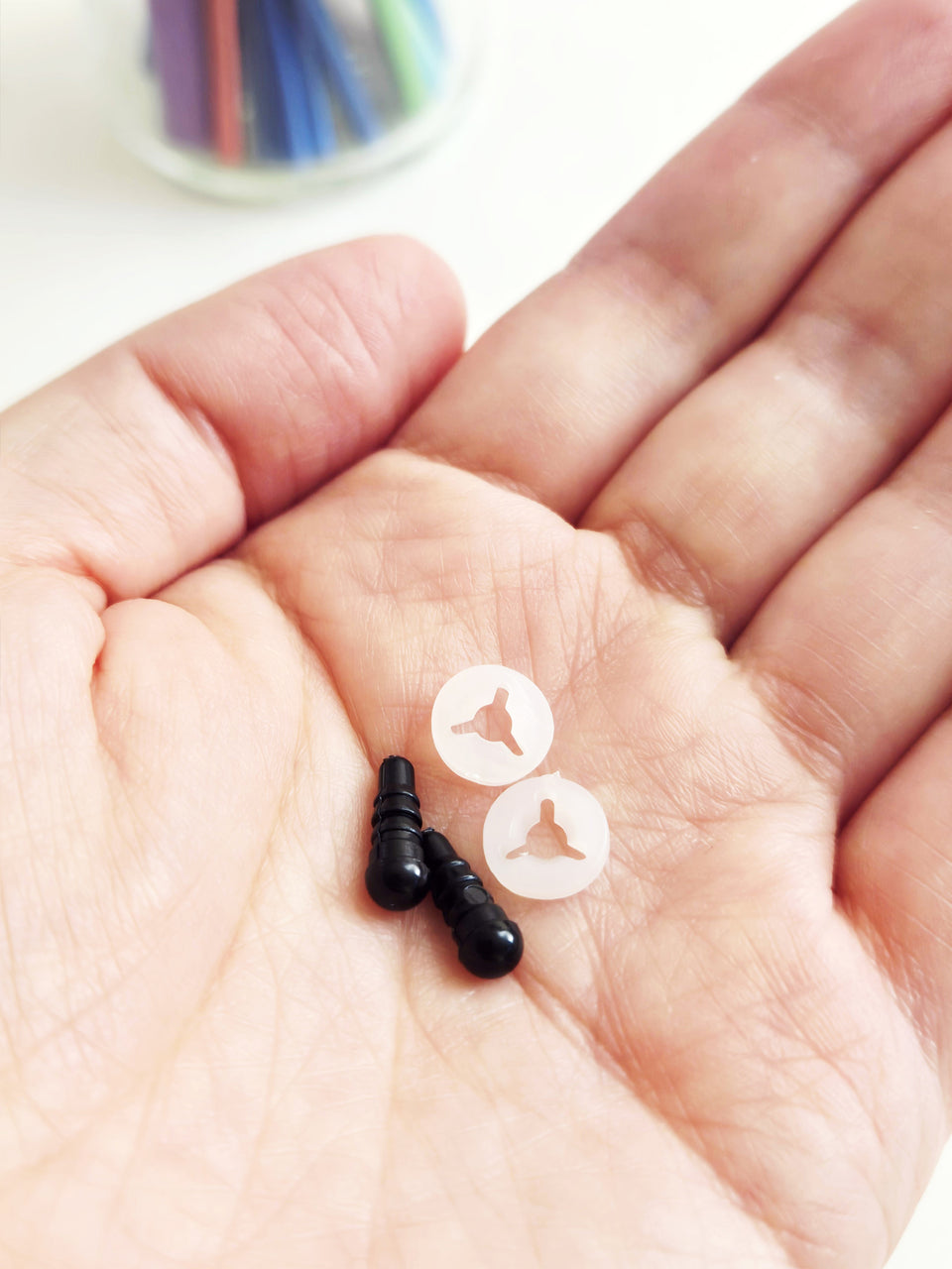pair of 4.5 mm black plastic safety eyes in palm of hand with plastic washers