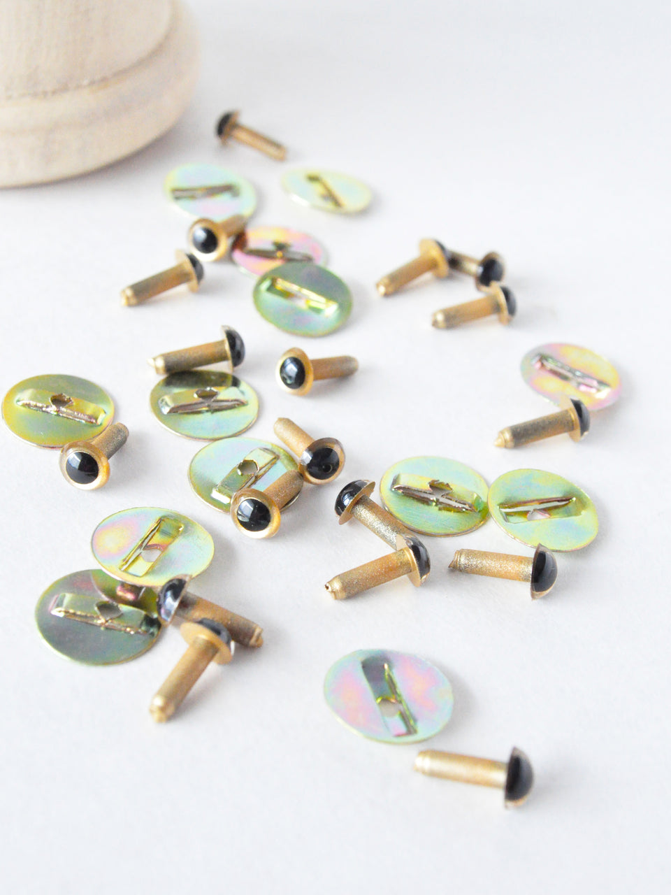 4.5 mm gold safety eyes and metal washers scattered on a white surface
