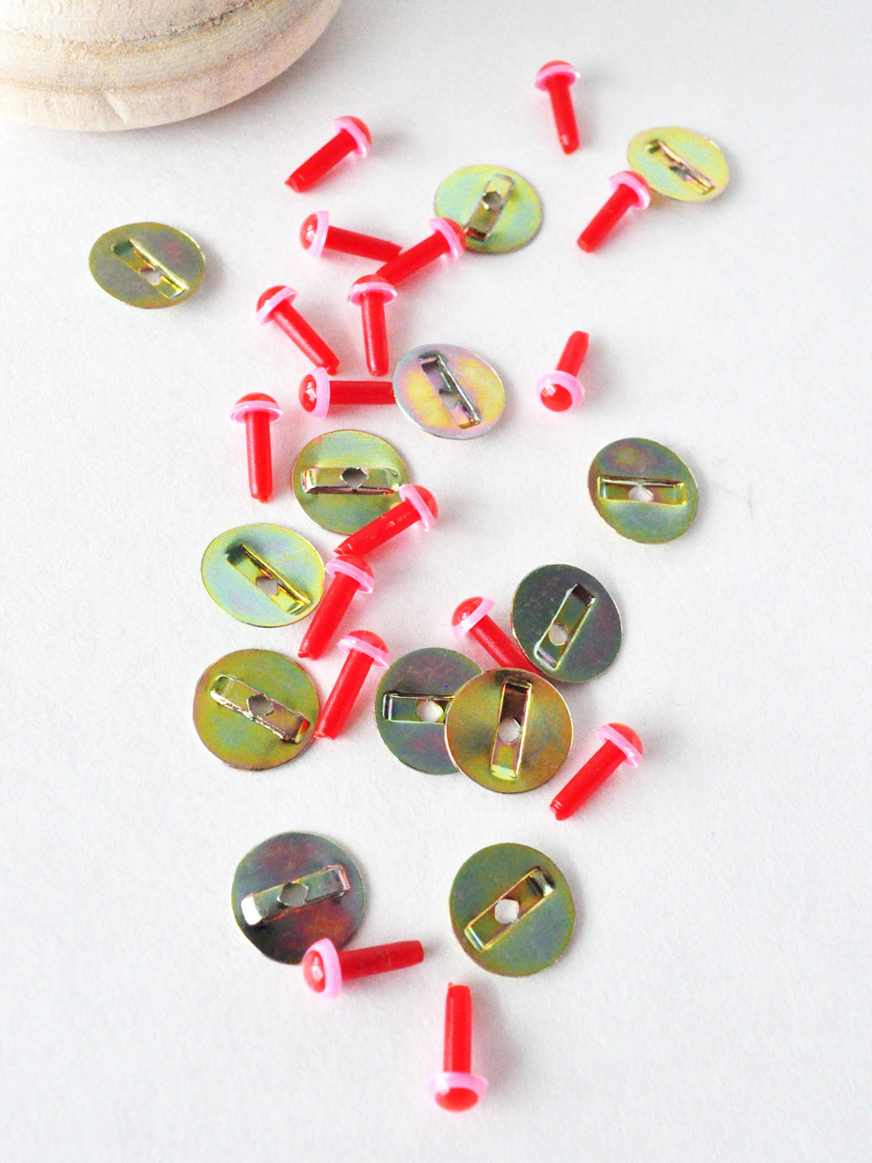 pink and red safety eyes with metal washers scattered on a white surface.