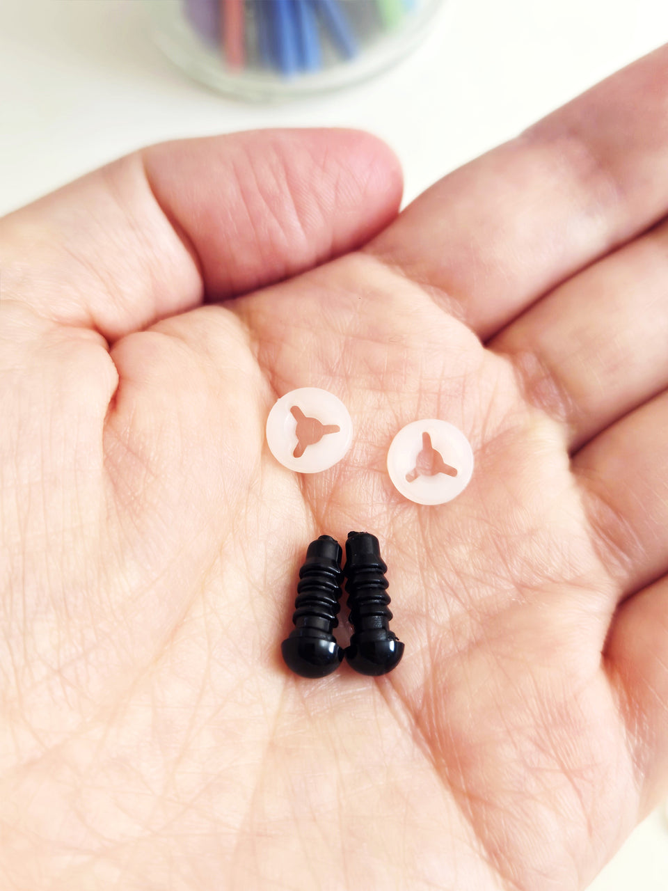 Pair of 6 mm safety eyes with washers in the palm of a hand