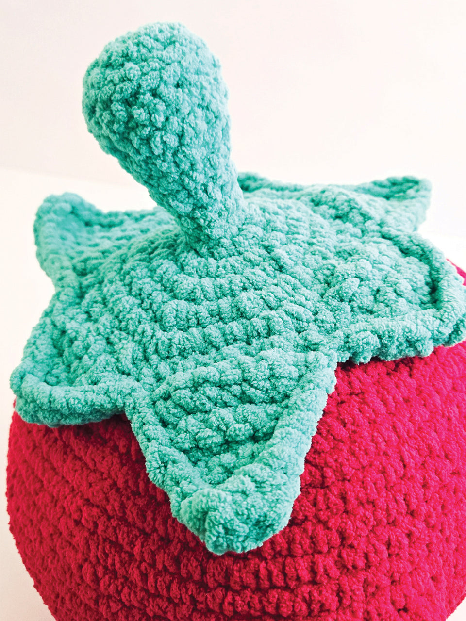 Crochet strawberry with a green leaf on a white background