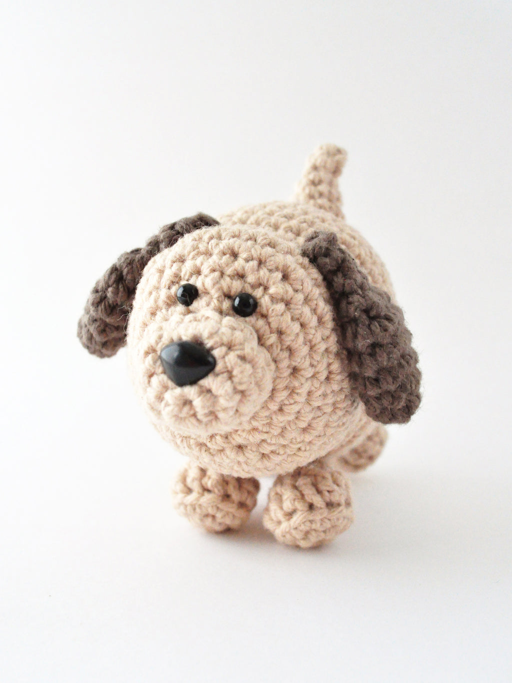 Crocheted brown and tan dog on a white background, amigurumi pattern by The Pudgy Rabbit.