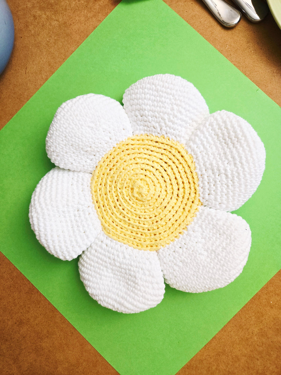 the back of a white and yellow crochet flower hot pad.