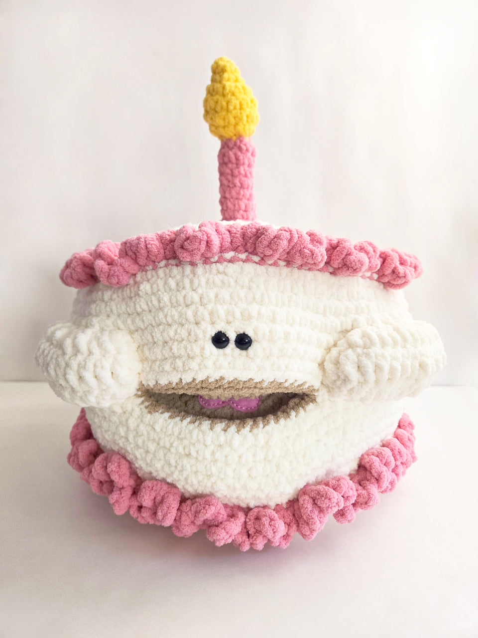 Crochet happy birthday cake with a candle on a white background