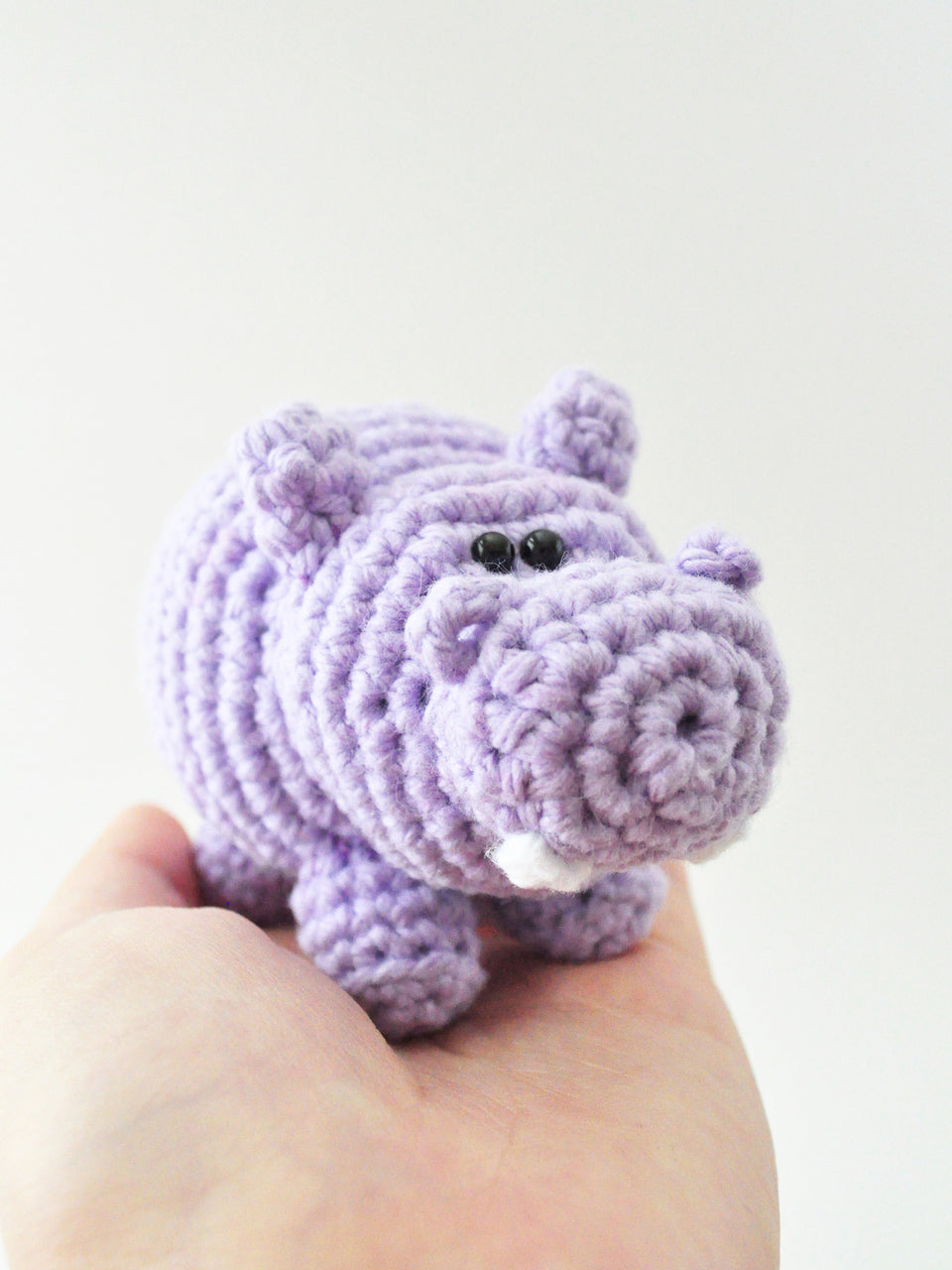 purple crocheted hippo being held in the palm of a hand