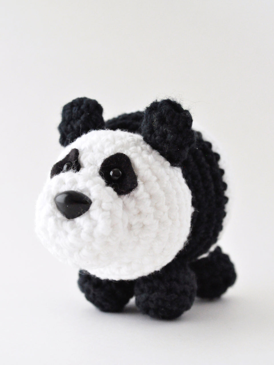 Crocheted panda toy on a white background made from pattern by The Pudgy Rabbit