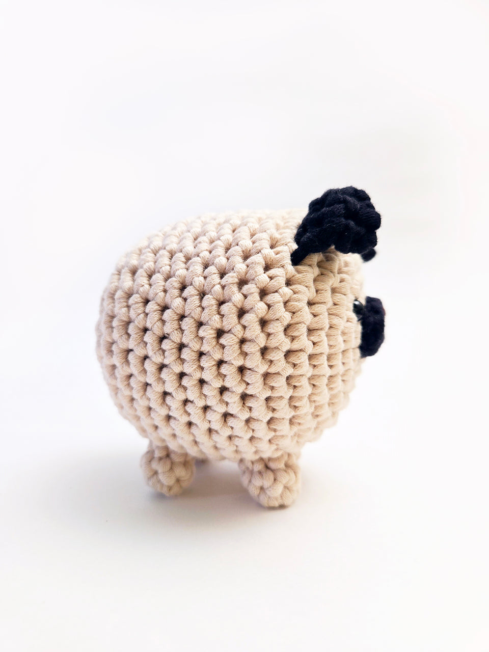 Side view of cream and black pug amigurumi.